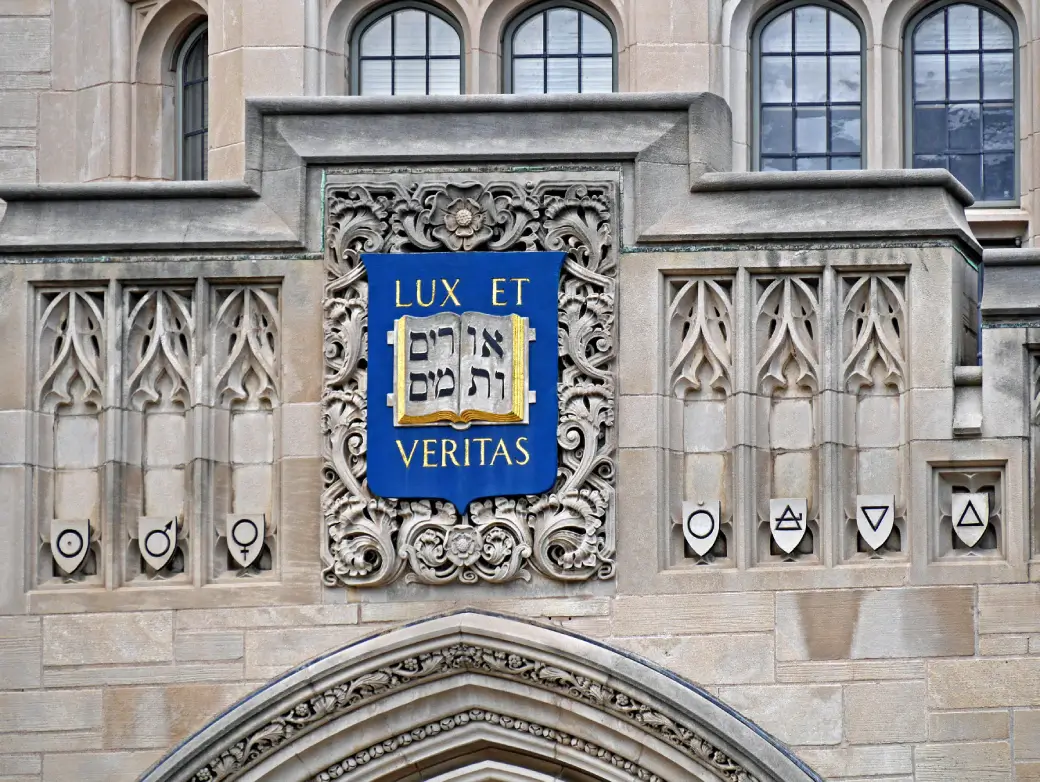 Yale crest with “Lux et Veritas” and Hebrew text on stone facade.